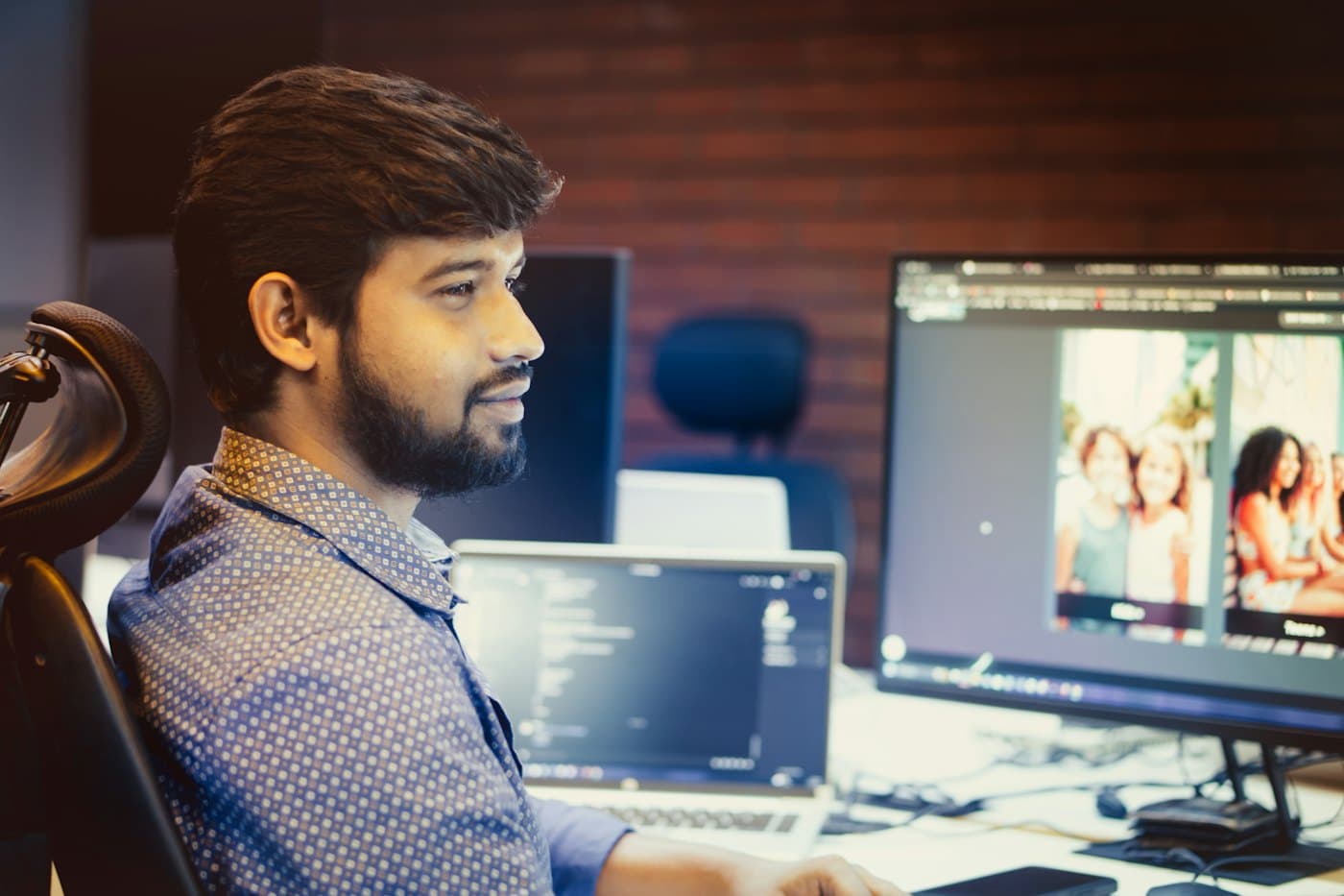 Developer smiling while building a website on a large monitor